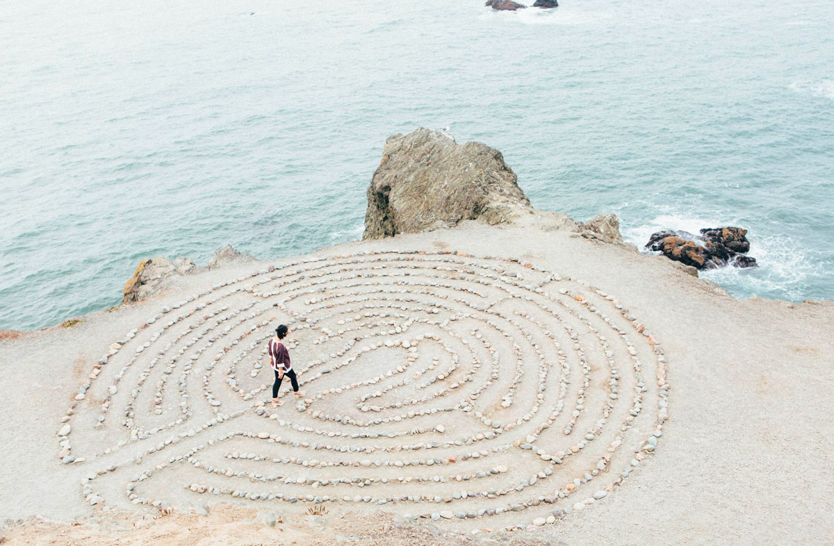 Man walking in a stone patterned design beside the cliff